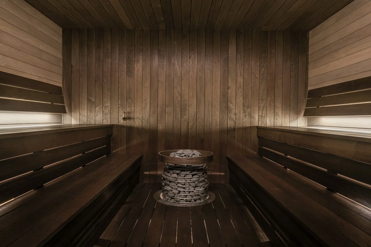 Real sauna interior with timber benches and a stone-filled heater